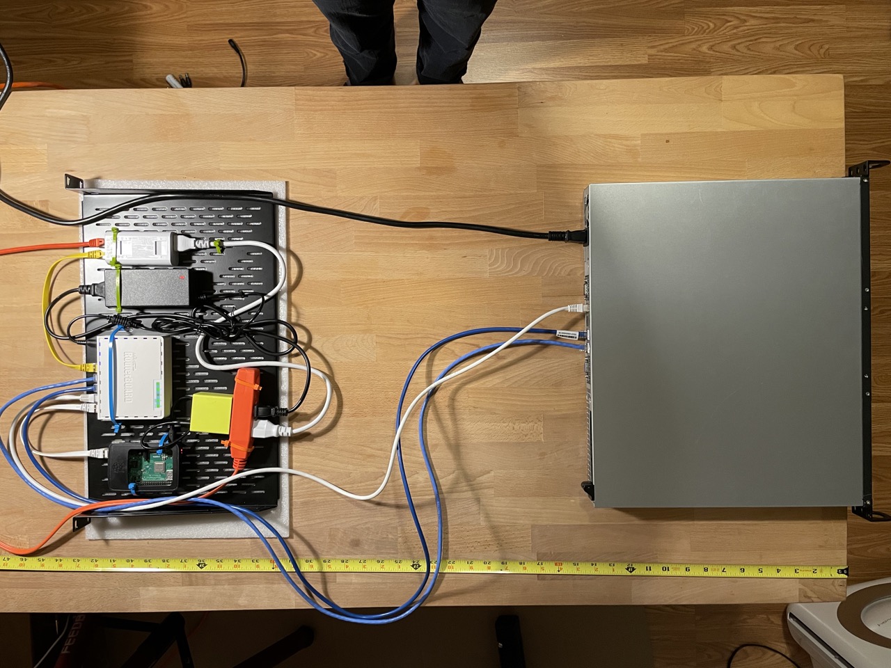 top-down photograph of table with small server and shelf with misc network gear and snaking cables