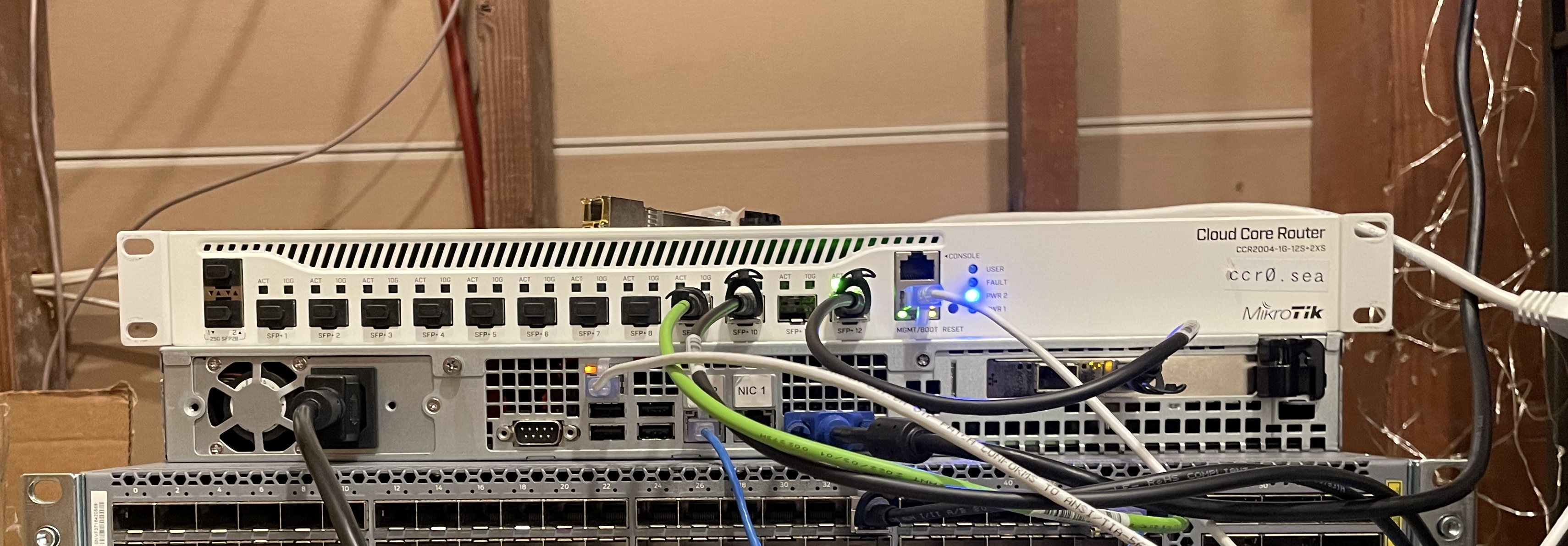 top-down photograph of table with small server and shelf with misc network gear and snaking cables